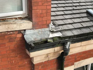 Guttering, downpipe and lead flashing on a slate-roofed bay