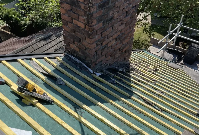 Pitched roof stripped to new battens and breathable membrane around a chimney